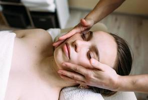 masseur faisant un massage sur le visage d'une femme au spa. le concept de procédures cosmétiques. photo