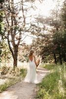 fille mariée heureuse dans une robe légère blanche avec un bouquet de fleurs séchées photo