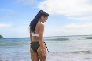 belle jeune femme en bikini profitant et se relaxant sur la plage, l'été, les vacances, les vacances, le concept de modes de vie. photo