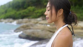 jeune femme asiatique en tenue de sport faisant du yoga sur le rocher au bord de la mer, concept de santé et de méditation photo