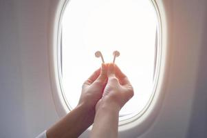 main de femme tenant des écouteurs sur un avion à fenêtre photo