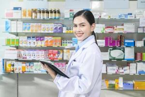 portrait d'une pharmacienne à l'aide d'une tablette dans une pharmacie de pharmacie moderne. photo