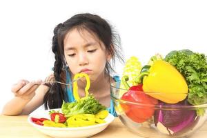 Jolie fille asiatique montrant une expression ennuyeuse avec des légumes frais colorés isolés sur fond blanc photo