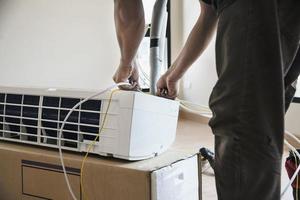 l'homme installe un climatiseur dans un logement pendant la saison chaude en thaïlande photo