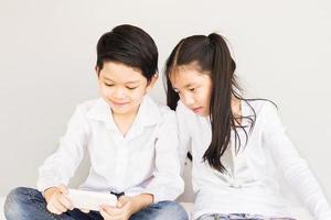 joli couple asiatique écoliers prennent selfie, 7 et 10 ans, sur fond gris photo