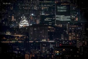 château d'osaka illuminé la nuit à vol d'oiseau ou vue de dessus avec paysage urbain et haut bâtiment autour, préfecture d'osaka, japon. photo