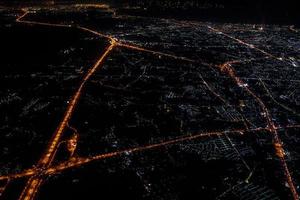 vue nocturne depuis l'avion à réaction au crépuscule avec le ciel rouge et la lumière de la ville. photo