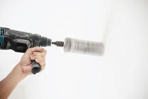 un technicien installe un climatiseur à l'aide d'une perceuse faisant un trou de tuyau pendant la saison chaude photo