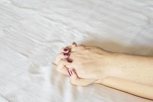 homme tenant la main de la femme sur le lit blanc, concept sexuel de couple photo