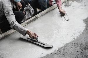 ouvrier faisant un travail de coulée de béton de surface de route sur un chantier de construction photo