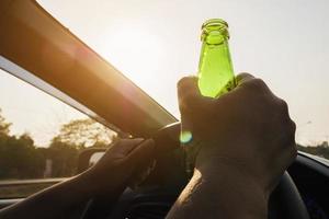 femme tenant une bouteille de bière en conduisant une voiture photo
