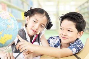 les enfants asiatiques étudient le globe dans leur classe photo
