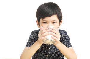 garçon asiatique boit un verre de lait sur fond blanc photo