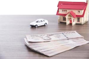 billet de banque thai baht argent avec modèle de voiture et de maison concept d'assurance financière immobilière photo