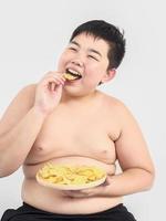 gros garçon mange joyeusement des chips photo