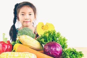 photo de style vintage d'une jolie fille asiatique montrant une expression de plaisir avec des légumes frais colorés isolés sur fond blanc