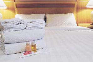 serviette d'hôtel avec shampoing et bouteille de savon sur lit blanc photo