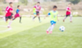 photo floue d'enfants pratiquant le football sur un terrain de football