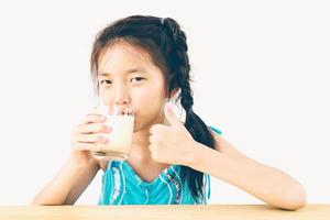 photo de style vintage d'une fille asiatique boit un verre de lait sur fond blanc