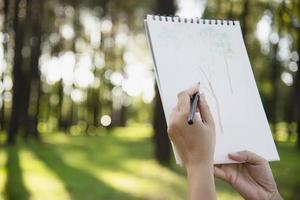 Détendez-vous femme peignant l'art de la couleur de l'eau dans la nature verte de la forêt de jardin - les personnes ayant de l'art créatif dans la nature concept de réduction du stress et de méditation photo