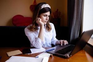 la fille travaille à l'ordinateur dans un café. étudiant apprenant en ligne. blogueur. jeune écrivaine caucasienne tapant sur un ordinateur portable. femme d'affaires attrayante utilisant un ordinateur portable pendant une pause. photo