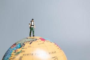 voyageurs en miniature, debout sur le globe et se dirigeant vers leur destination, photo