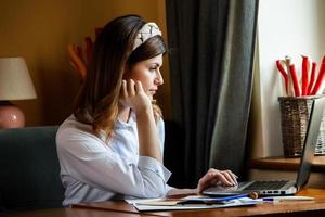 la fille travaille à l'ordinateur dans un café. étudiant apprenant en ligne. blogueur. jeune écrivaine caucasienne tapant sur un ordinateur portable. femme d'affaires attrayante utilisant un ordinateur portable pendant une pause. photo