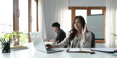 femme asiatique parlant de rapport de vente en vidéoconférence. équipe asiatique utilisant un ordinateur portable et une tablette en ligne lors d'un appel vidéo.travail à distance à domicile. photo