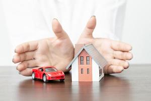 jeune femme utilise deux mains pour protéger le modèle de maison. photo