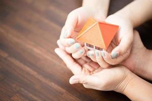 les mains masculines et féminines tiennent une petite maison. photo