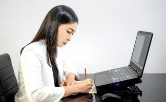 la femme d'affaires asiatique tenue décontractée utilisant un ordinateur portable travaillant dans le salon à la maison. photo