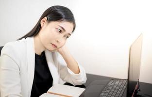 les jeunes asiatiques ressentent le stress du travail, assis devant l'ordinateur portable dans leur maison. photo