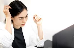 les jeunes asiatiques ressentent le stress du travail, assis devant l'ordinateur portable dans leur maison. photo