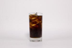 un verre de cola noir avec de la glace est rempli sur fond blanc photo