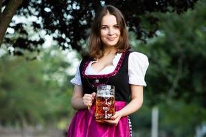 femme russe sexy en robe bavaroise tenant des chopes à bière. photo