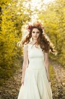 jeune femme tenant un tas de feuilles d'érable jaune. portrait d'automne de jeune femme. fille aux cheveux rouges dans la forêt d'automne photo