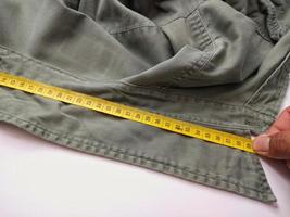les jeans à main tirent le ruban à mesurer jaune. photo