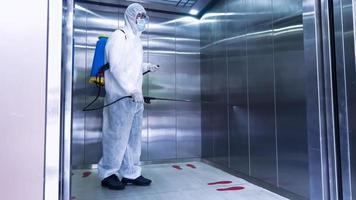 travailleur en costume d'équipement de protection individuelle nettoyant dans le bâtiment avec de l'eau désinfectante en aérosol pour éliminer le covid 19 photo