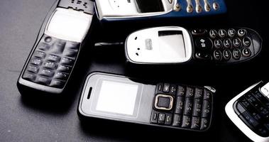 tas de téléphones portables vintage sur fond noir. photo