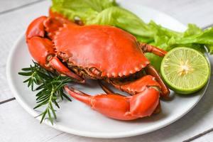 assiette de fruits de mer aux herbes épices romarin salade de citron vert laitue légume, crabe frais sur assiette blanche, crabe cuisson des aliments bouillis ou cuits à la vapeur crabe rouge au restaurant photo