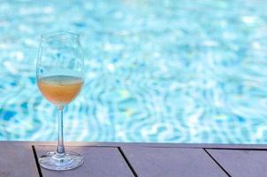 un verre de vin rosé posé sur la piscine. photo