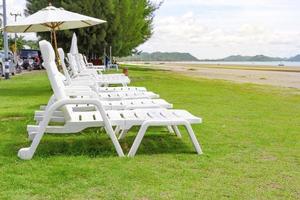 chaise de plage blanche et parasol sur la plage tropicale avec ciel bleu photo