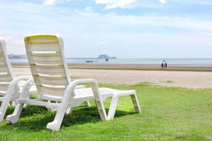 Chaise de plage blanche sur la plage tropicale avec ciel bleu photo