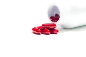 pilules rouges et bouteille de pilules sur blanc isolé photo