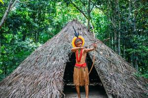 indien de la tribu pataxo utilisant un arc et des flèches. indien brésilien avec coiffe de plumes et collier