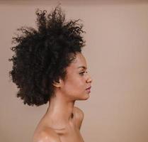 à côté d'une jeune femme afro latine souriante. joie, positif et amour. beaux cheveux de style africain. fond de studio pastel. photo