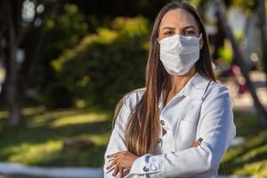 femme médecin brésilienne souriante en blouse blanche. les bras croisés. photo