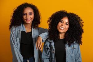 deux jeunes femmes afro-américaines aux cheveux bouclés regardant la caméra et souriant. jolies filles afro aux cheveux bouclés souriantes regardant la caméra. photo