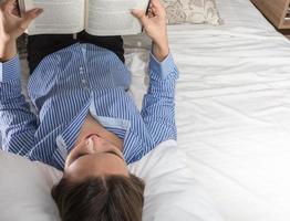 concept de loisirs et de personnes - jeune femme lisant un livre au lit photo