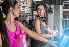 belles femmes s'entraînant dans une salle de sport. beau groupe d'amies de jeunes femmes exerçant sur un tapis roulant dans la salle de sport moderne et lumineuse. photo